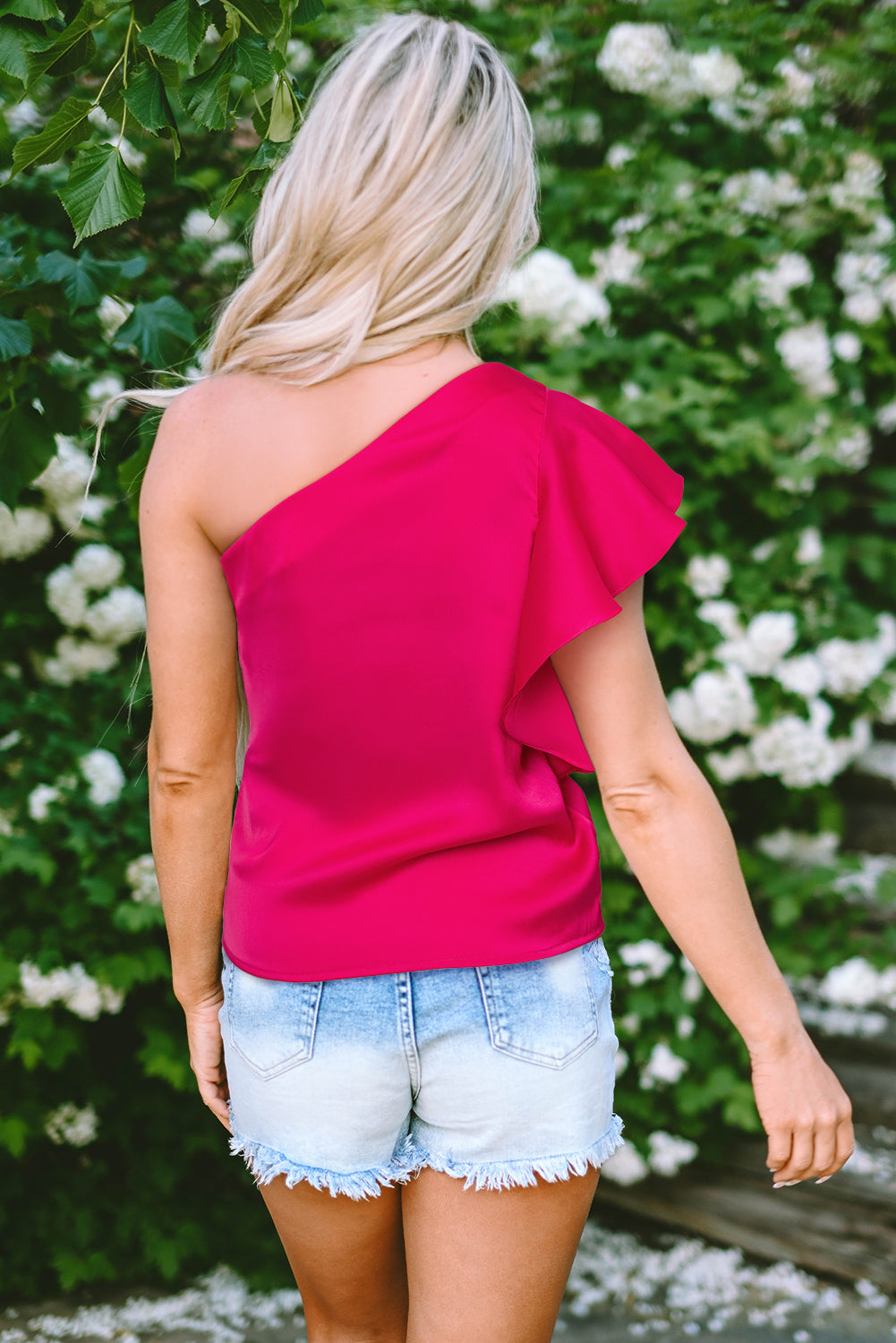 Blusa elegante con hombros asimétricos y mangas con volantes en color rosa fresa