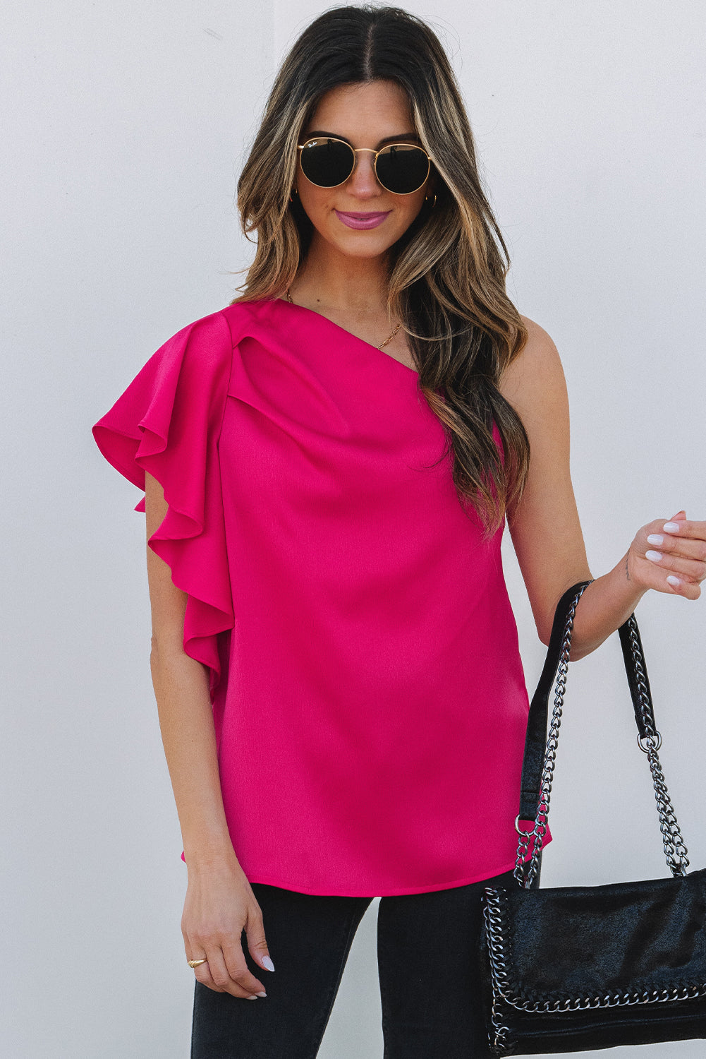 Blusa elegante con hombros asimétricos y mangas con volantes en color rosa fresa