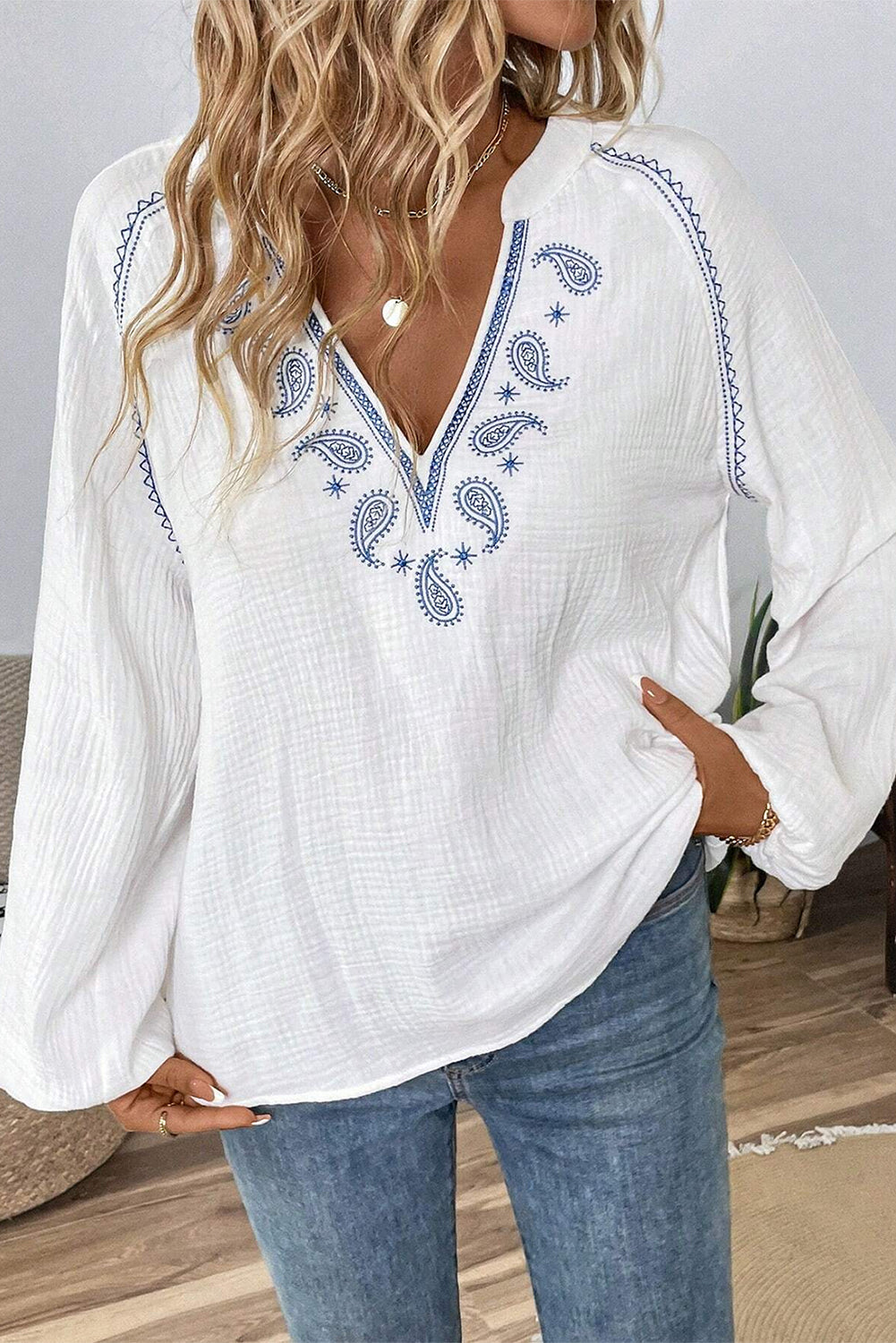 Blusa blanca con mangas largas abullonadas, cuello abierto y textura bordada con cachemira