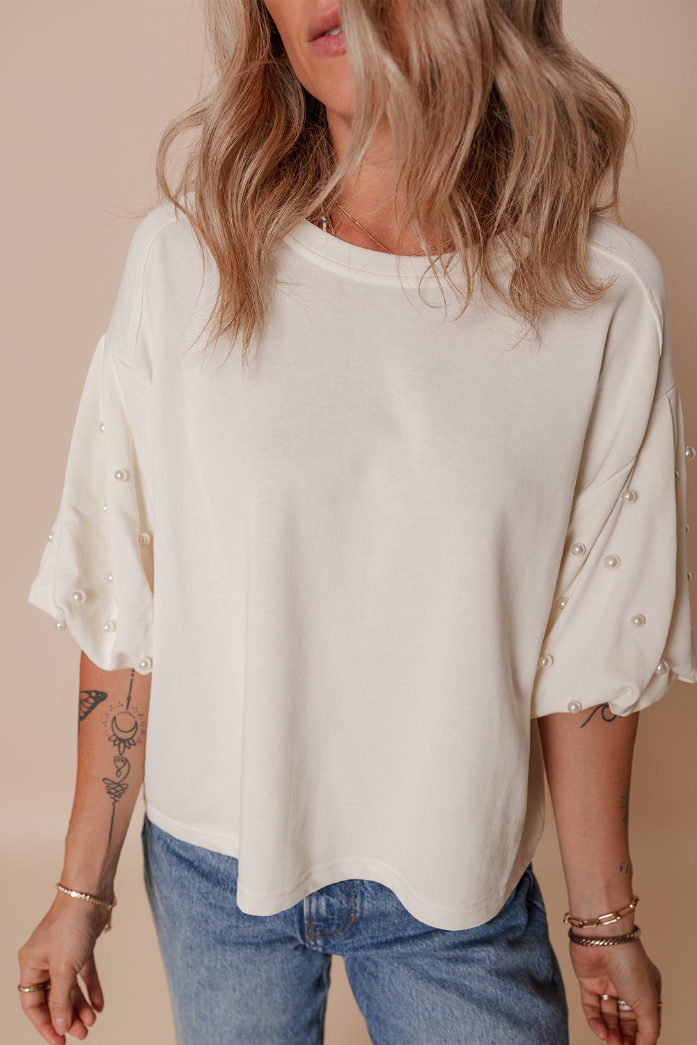 Blusa holgada con cuello redondo y mangas abullonadas con detalles perlados en color blanco