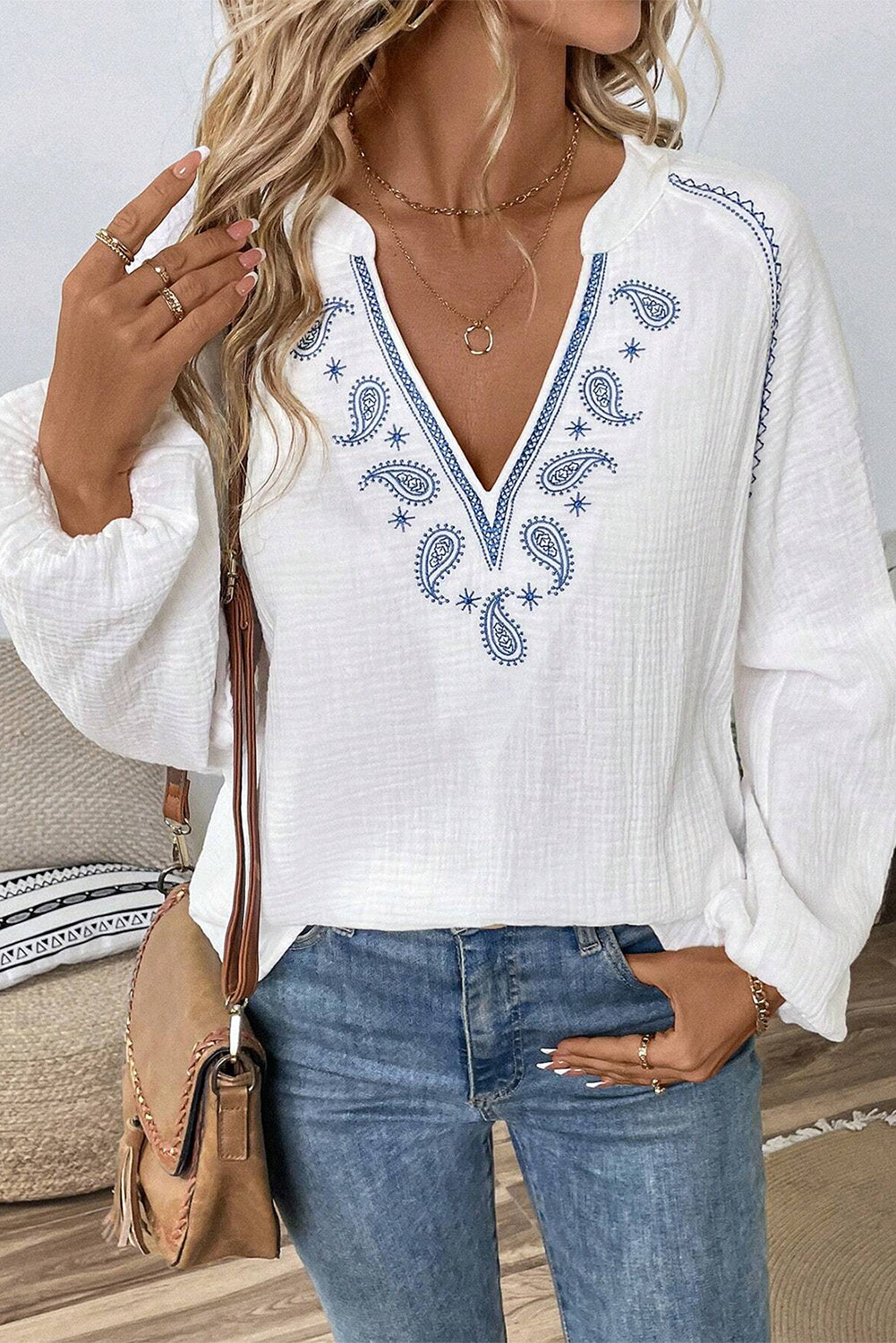 Blusa blanca con mangas largas abullonadas, cuello abierto y textura bordada con cachemira