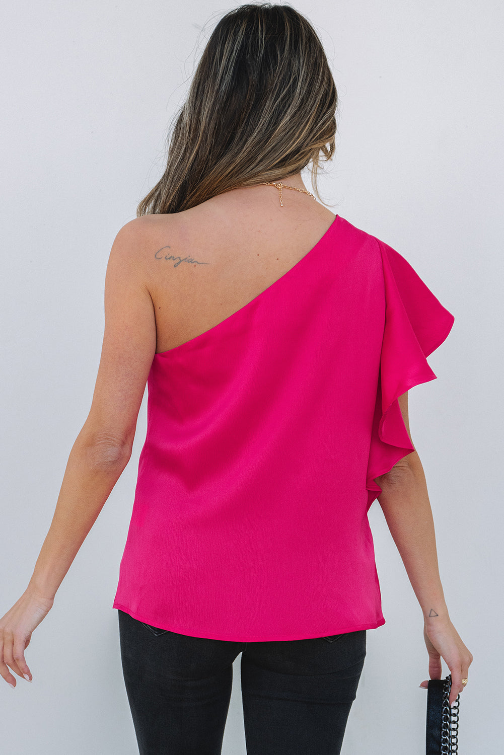 Blusa elegante con hombros asimétricos y mangas con volantes en color rosa fresa