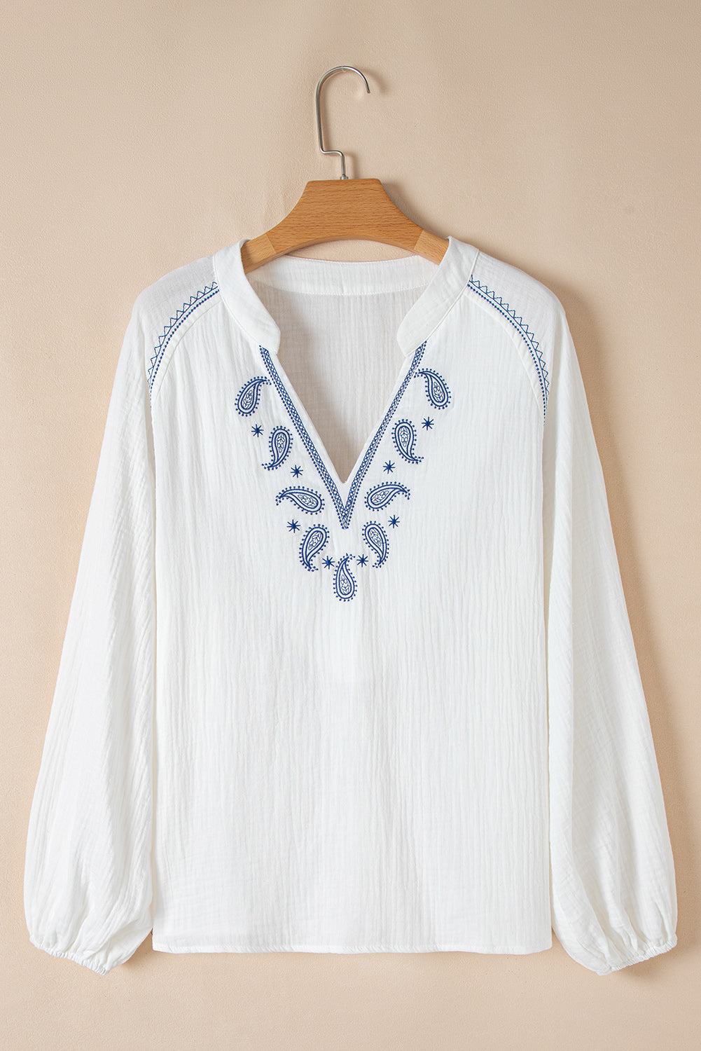 Blusa blanca con mangas largas abullonadas, cuello abierto y textura bordada con cachemira