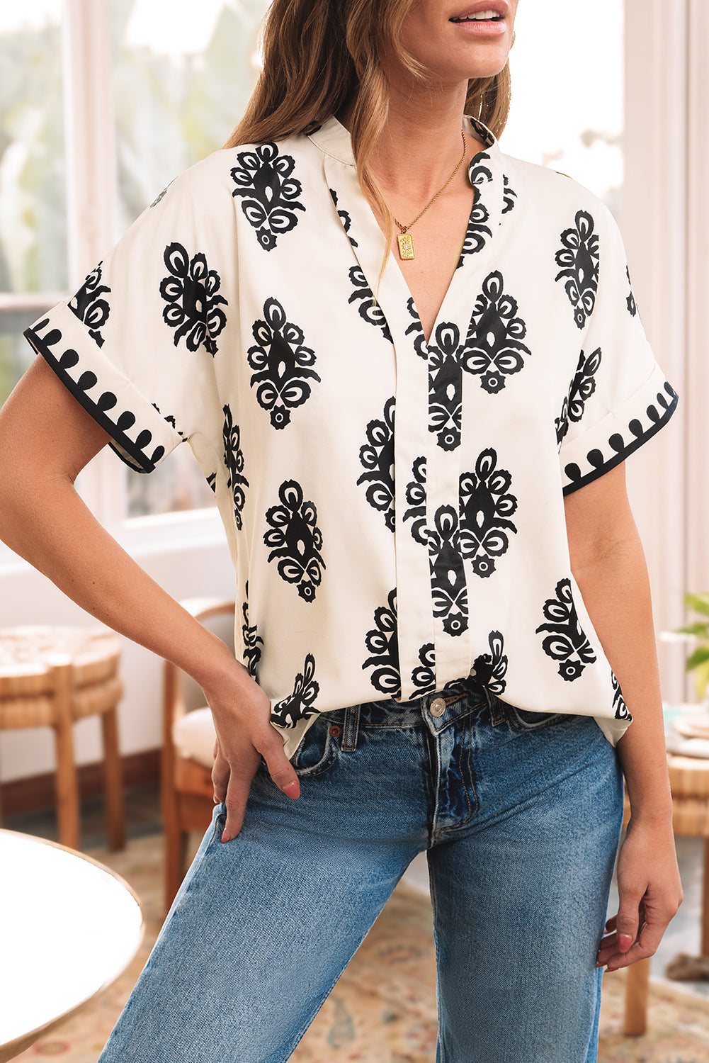 Blusa negra con cuello en V y manga corta con estampado geométrico